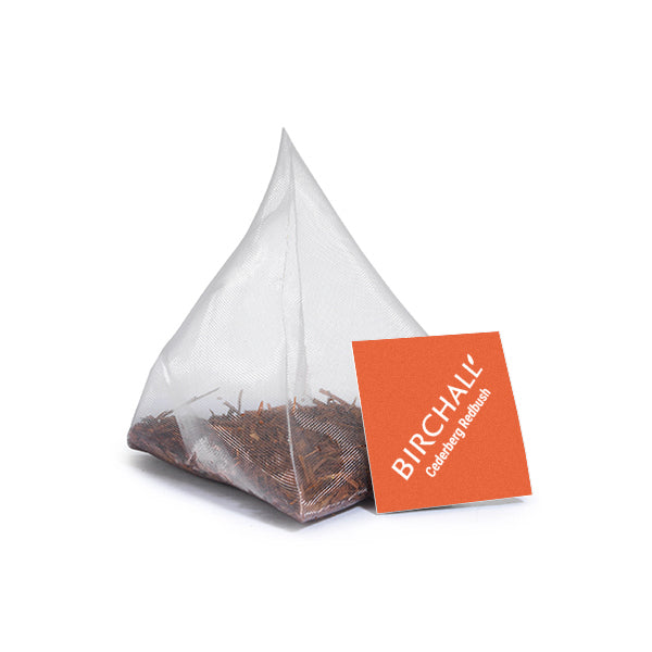 A single prism orange tagged tea bag of Birchall Organic Redbush tea. Mesh tea bag with large loose leaf inside.